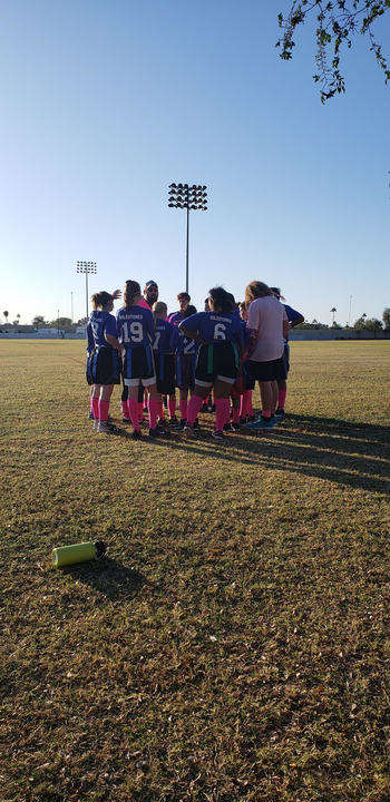 Coach Ray huddles with the Mustangs flag football team